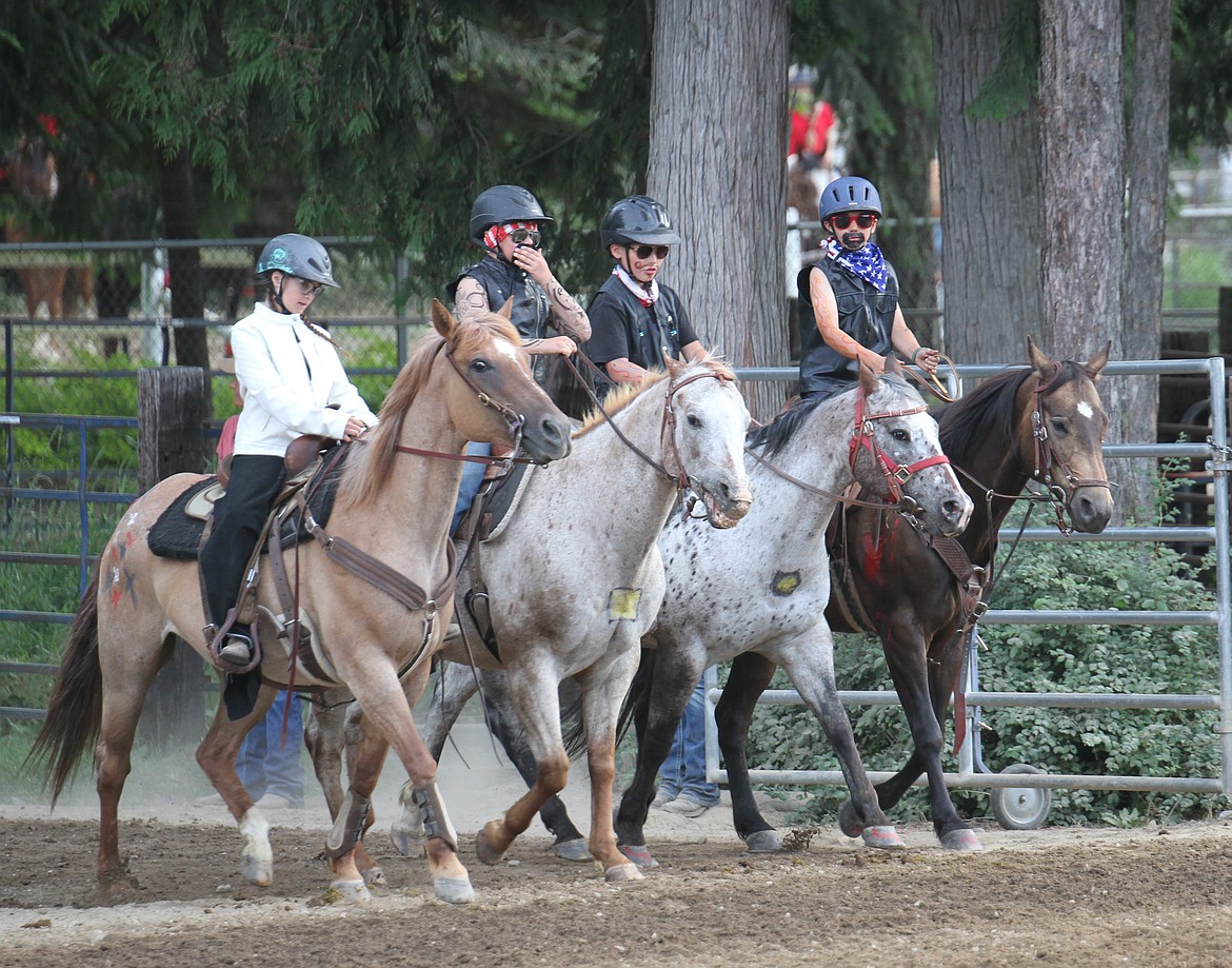 Four riders from the 'Rough Riders' group enter the main gate, ready to start their performance.