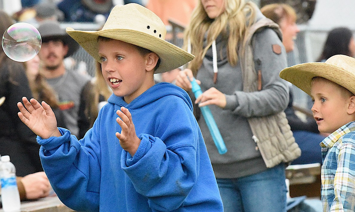 This young man enjoyed chasing bubbles while the tractor crew worked up the area for barrel racing. (Berl Tiskus/Leader)