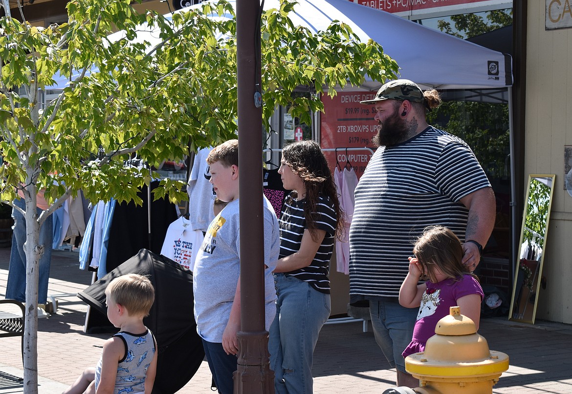 A family watches competitors toss bean bags at the cornhole competition.