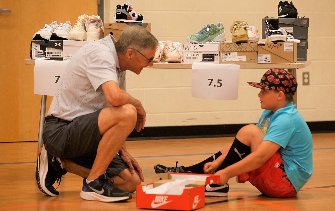 Volunteer Brad Baldwin helps Jaxon Gray try on shoes at the Lola and Duane Hagadone Boys and Girls Club on Tuesday.