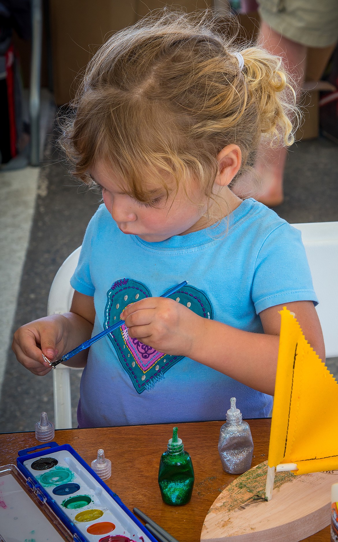 A youngster concentrates as she works to decorate the small wooden boat she was building as part of a Sandpoint Boat Show children's boat building event.