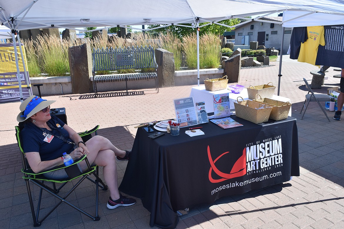 Moses Lake Museum and Art Center Superintendent Dollie Boyd sits at the Museum’s informational booth in Sinkiuse Square, ready to talk with members of the public about the Museum’s services.