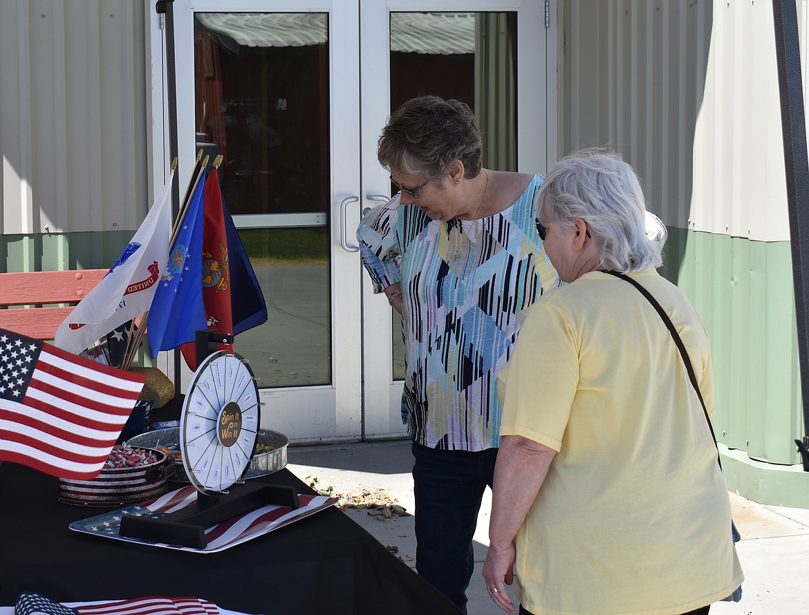 Terri Moncrief, left, and Pam Hill wait to see what prize they’ve won from the spinning wheel at the Movement Mortgage booth at the Senior Picnic June 14.