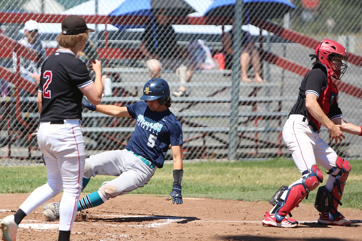 River Dog catcher Holden Koziol (5) slides into home plate in between two Absolute Human Performance Academy players.