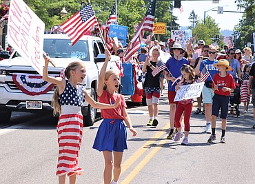 Esther Van White, left, and Juliet Claridge wave to the crowd as they walk in the Coeur d'Alene Regional Chamber's Fourth of July parade with others on Tuesday.