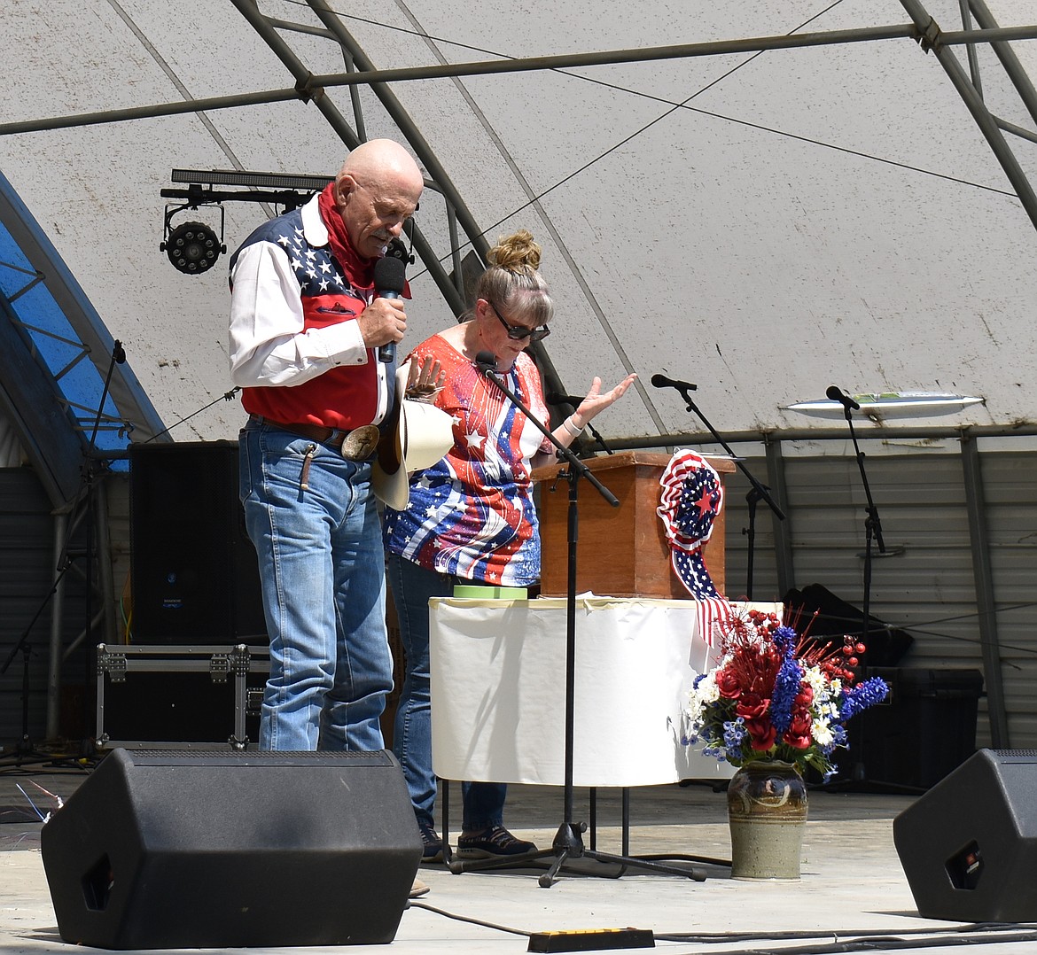 State Rep. Tom Dent, left, with George resident Debby Kooy, leads the crowd in prayer at George’s Fourth of July festivities Tuesday.