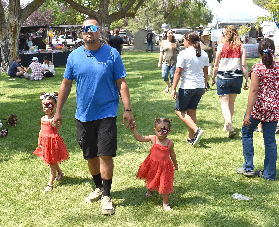 Zack Villalpando walks through the Independence Day celebration in George Tuesday with his daughters 3-year-old Vaelynn and  2-year-old Haisley.