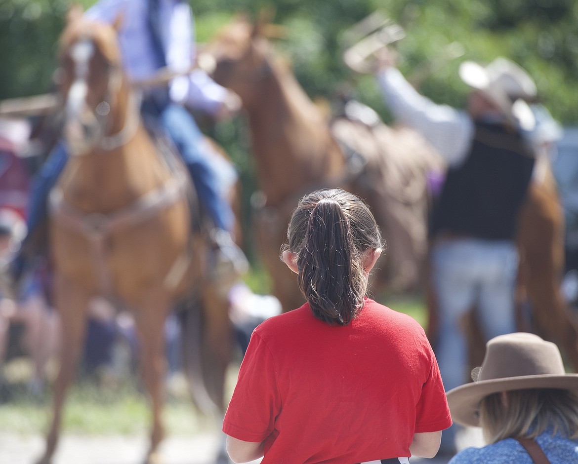 A little girl watches as horses are directed through the streets of Arlee during it's annual Independence Day celebration. (Max Dupras/Leader)