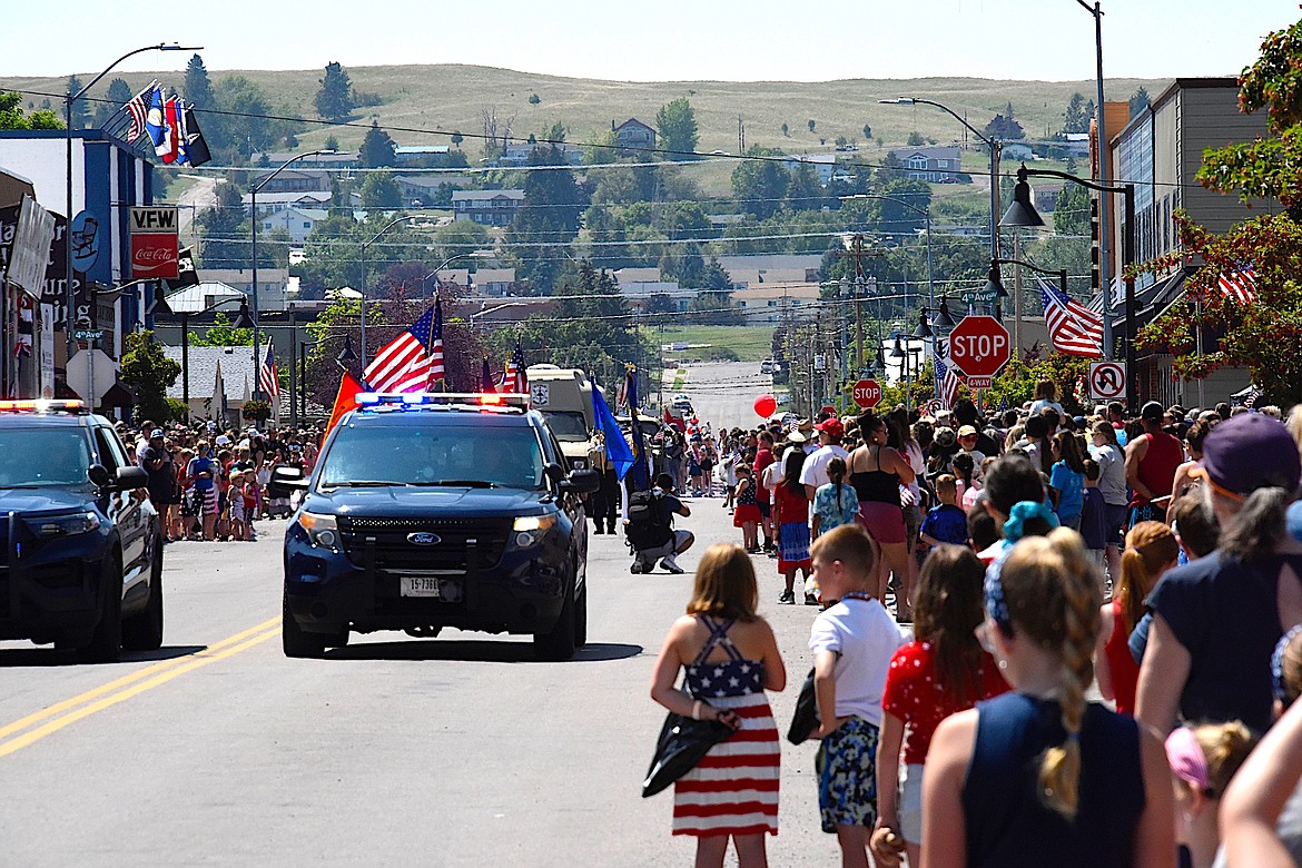 City of Polson Police cars led the Fourth of July parade down Main Street, delighting kids who were waiting for candy, floats, and waving to friends. {Berl Tiskus/Leader)