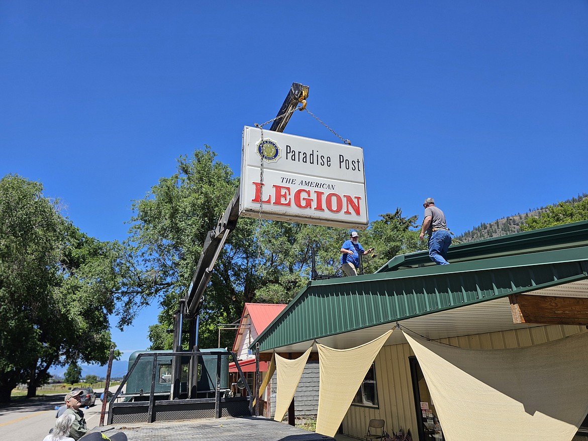 The Paradise American Legion club sign, which survived a major fire the razed the club 10 years ago, is lifted back into place above the entrance to the club which front Montana 200. (Chuck Bandel/VP-MI)