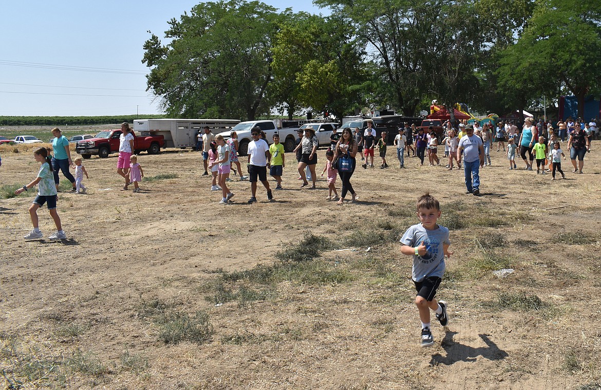 Children dash into the field next to Lions Park in pursuit of ping pong balls dropped from the sky at Summerfest in Royal City Saturday.