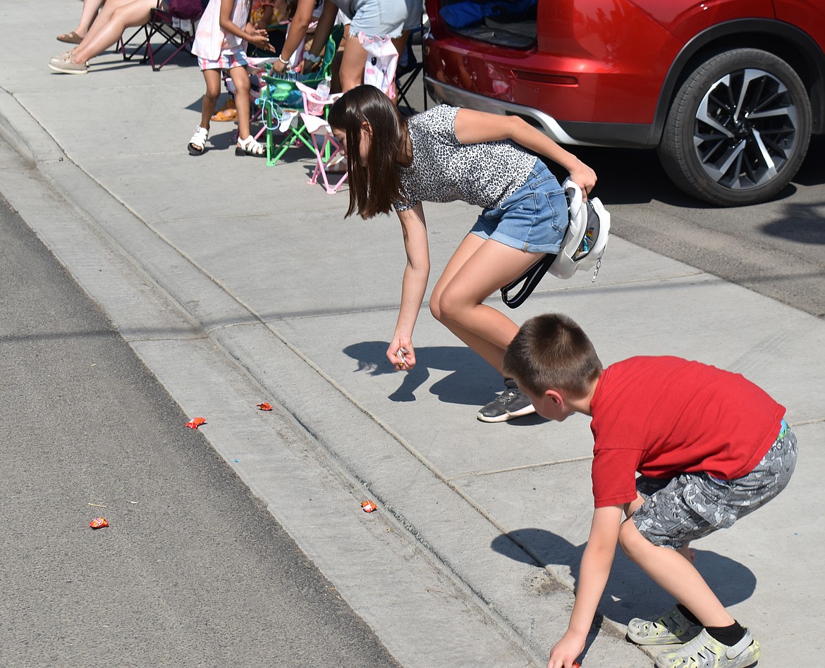 Twelve-year-old Natalia Abundiz, left, and her brother Emilio Abundiz, 6, pick up candy at the Summerfest parade Saturday morning.