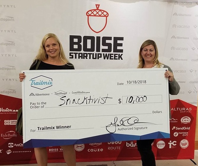 Joni Kindwall-Moore (left) receives a giant check for winning Trailmix competition at Boise Entrepreneur Week.