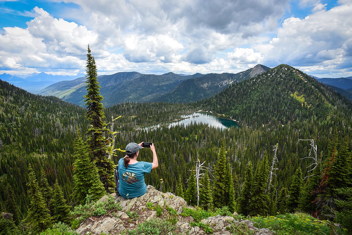 A hiker takes a photo on a rock ledge over Link Lake in Flathead National Forest on Sunday, June 11. (Casey Kreider/Daily Inter Lake)