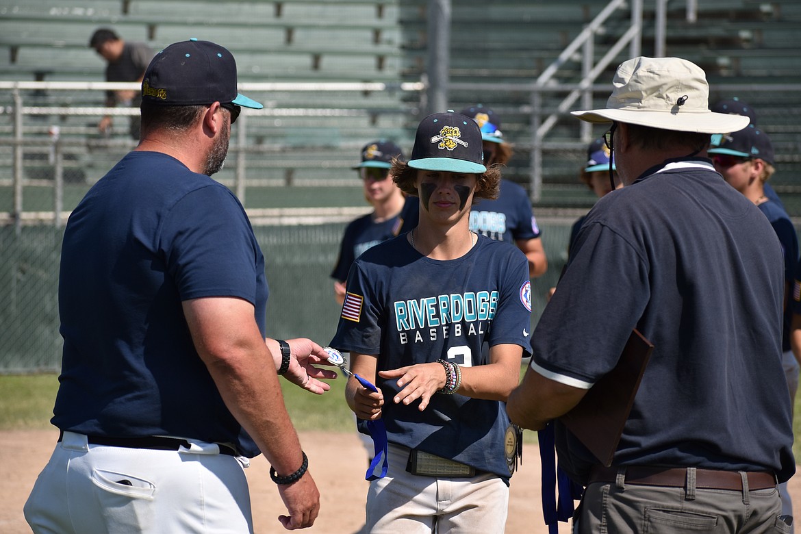 A 14U River Dogs player, center, receives a championship medal from Head Coach Jaret Fulbright, left, after the River Dogs defeated Stilly Venom 4-1 in the title game.