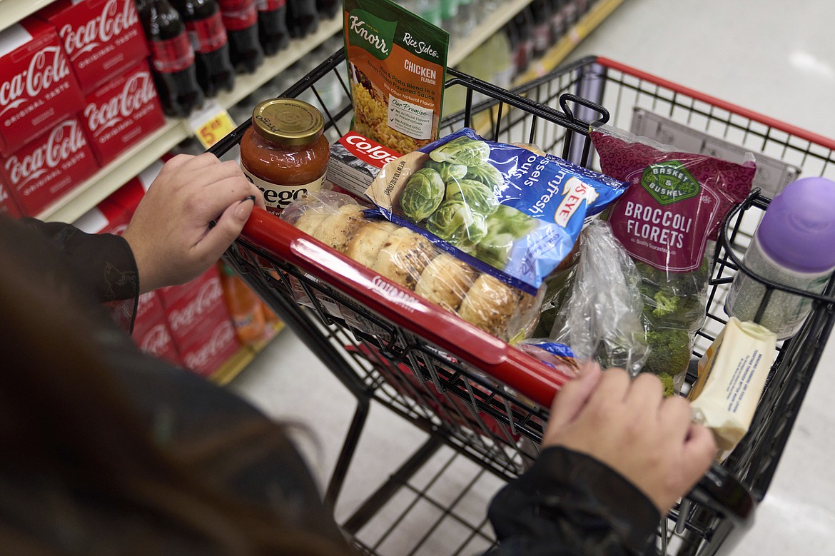 File - A food shopper pushes a cart of groceries at a supermarket in Bellflower, Calif., on Monday, Feb. 13, 2023. Over the past 12 months, gas prices have dropped, grocery costs have risen more slowly and used cars have become less expensive.(AP Photo/Allison Dinner, File)