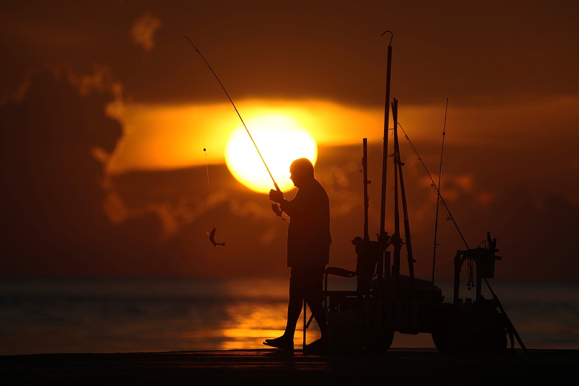 A fisherman reels in his catch as the sun rises over the Atlantic Ocean, June 28, 2023, in Bal Harbour, Fla. An already warming Earth steamed to its hottest June on record, with global oceans setting temperature records for the third straight month, the U.S. National Oceanic and Atmospheric Administration announced Thursday, July 13. (AP Photo/Wilfredo Lee, File)