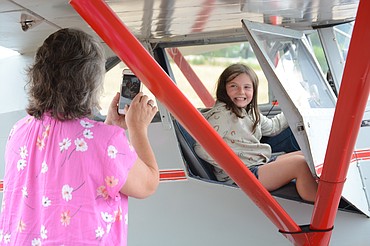 Autumn Smith, 9, of Wardner, sits in the pilot's seat of an antique plane as Terri Smith, Mullan, snaps a photo. 30 planes visited the Shoshone County airport Tuesday as part of the Puget Sound Antique Airplane Club air tour.