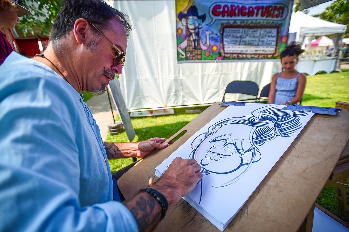 Artist Corey Ruffin works on a caricature of Isley Parkman, from Lakeside, at the Hockaday Museum's Arts in the Park festival at Depot Park on Friday, July 14. The festival also features food and specialty booths, live music and entertainment from over 40 performers, a premium wine and beer garden and a new community corner with booths and activities presented by local institutions. (Casey Kreider/Daily Inter Lake)