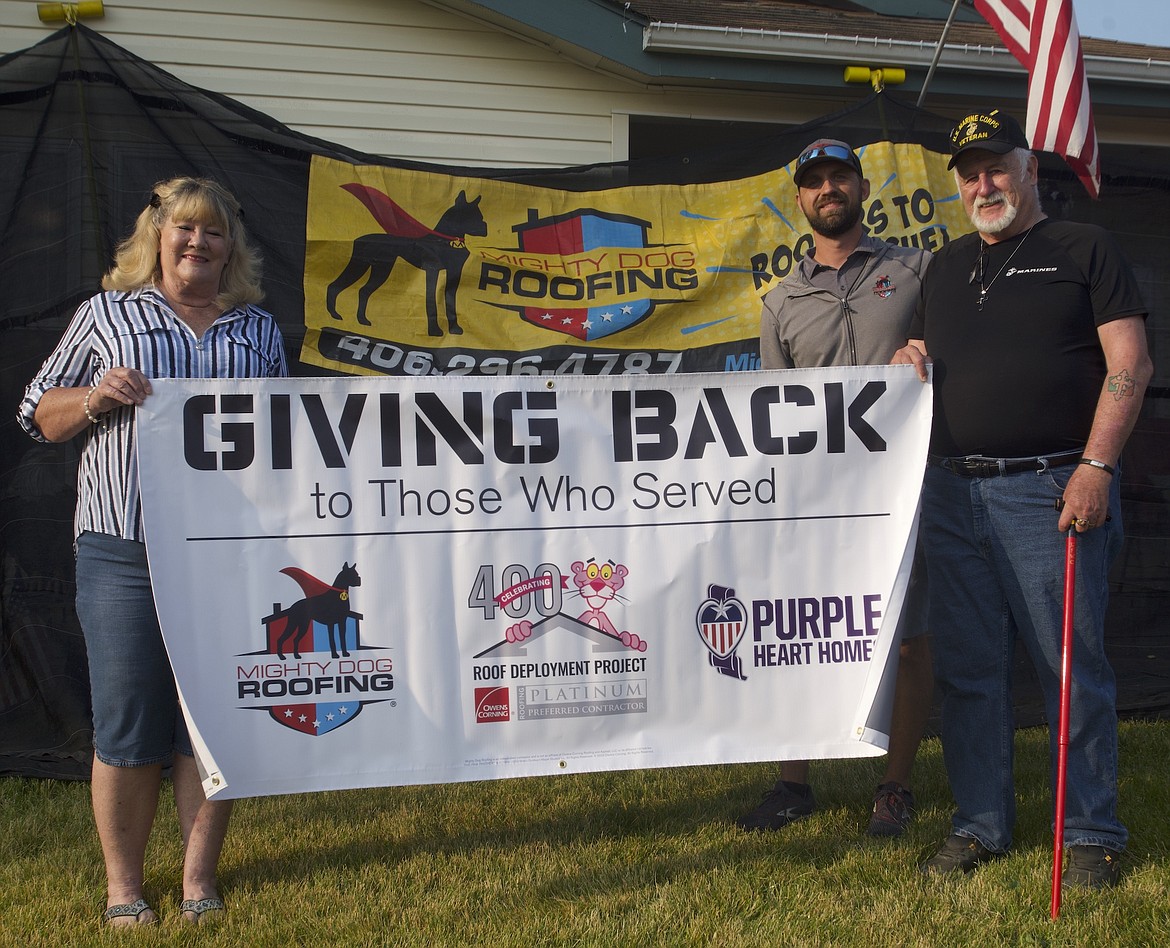 Nick Whitehead stands with U.S. Marine Corps veteran Edward Anthony and his wife Debby in front of their house.