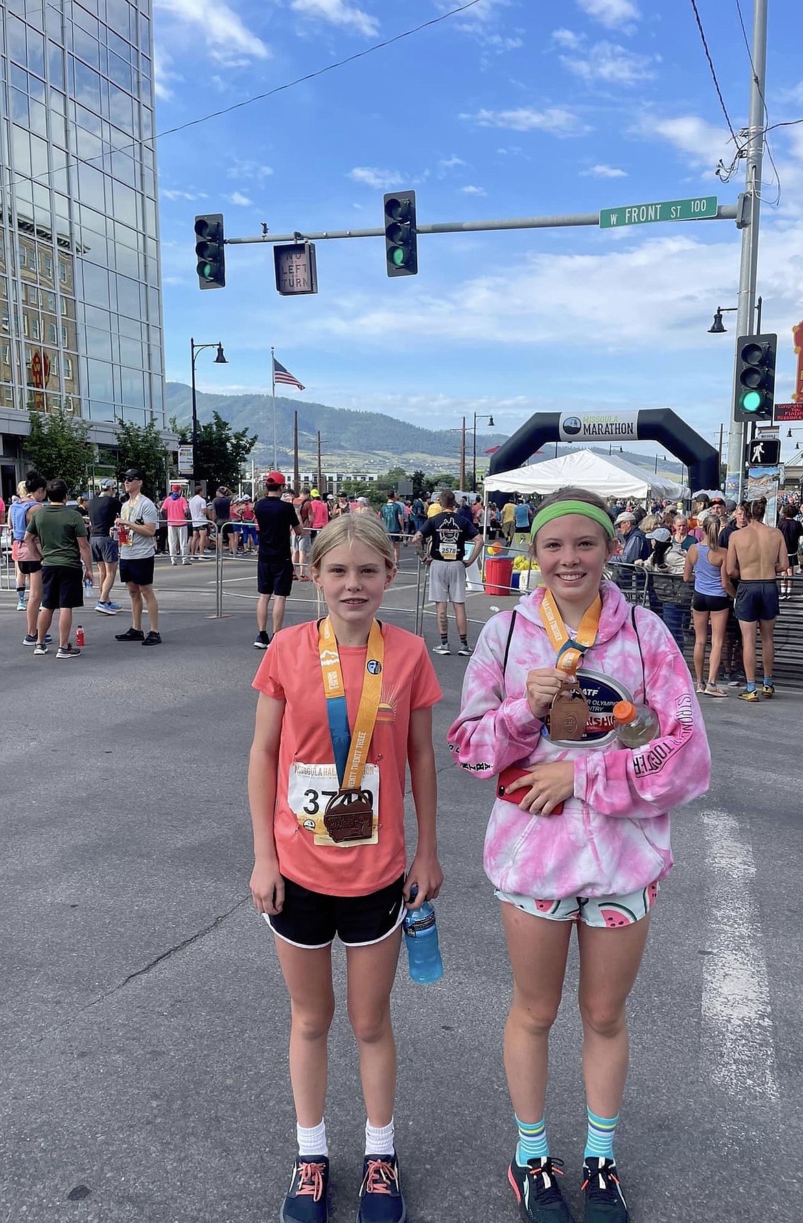 Quinn and Morgan Delaney show off half-marathon medals in downtown Missoula.
