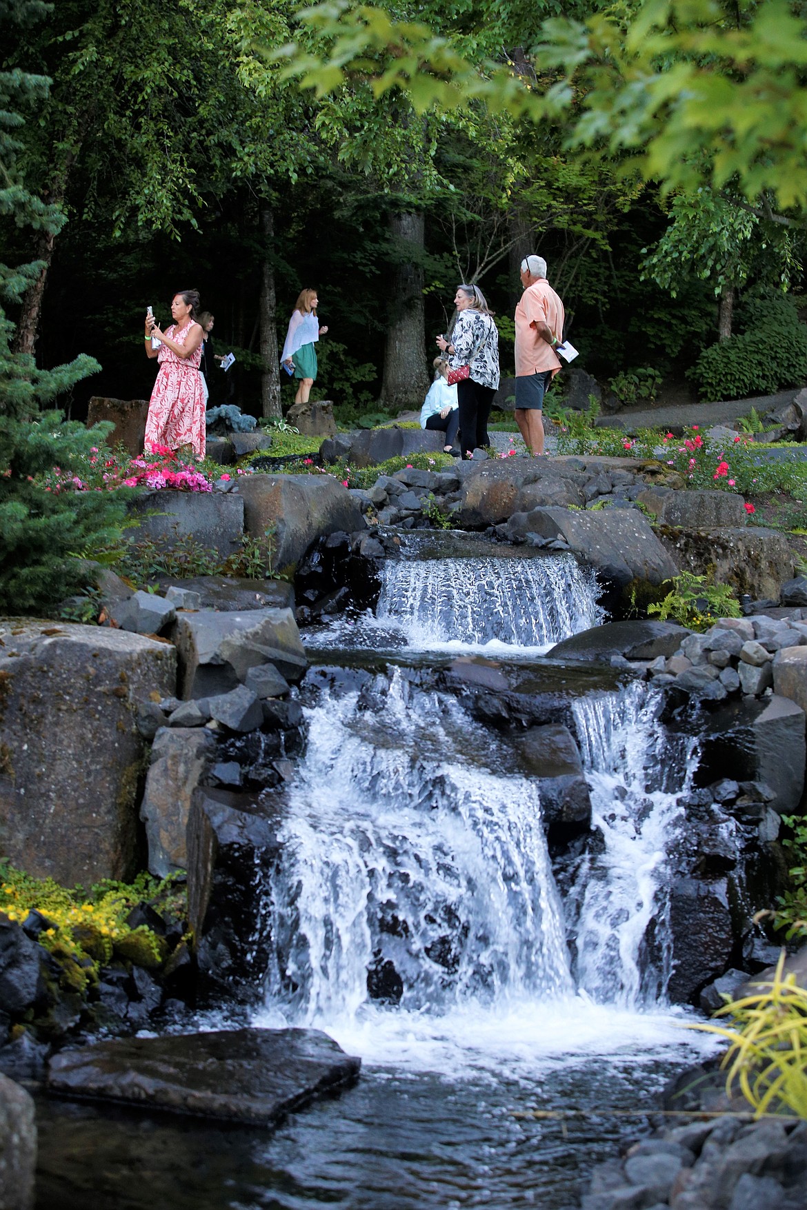 Guests stand near a waterfall at Hagadone Gardens on Tuesday.