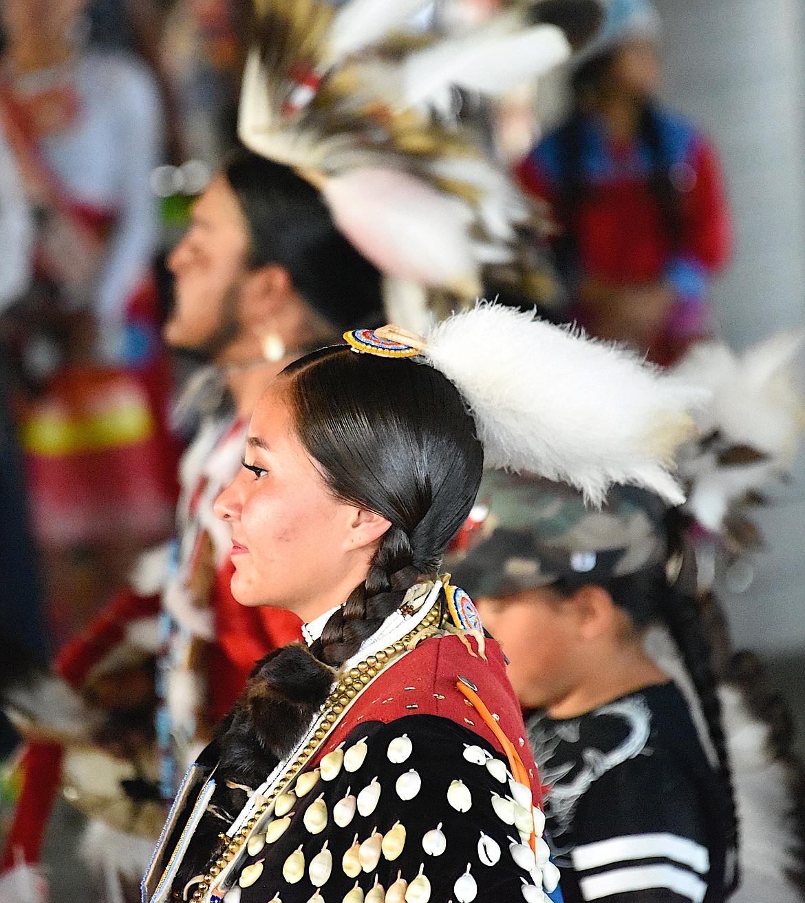 A poised young woman wearing regalia decorated with elk teeth enters the dance pavilion for the Standing Arrow Powwow. (Berl Tiskus/Leader)