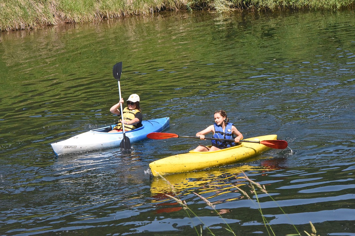 Maura Murer (blue kayak) and Brynn Deshazer (yellow kayak) paddle back from a trip down the Yaak River on Friday, July 7, 2023. (Scott Shindledecker/The Western News)