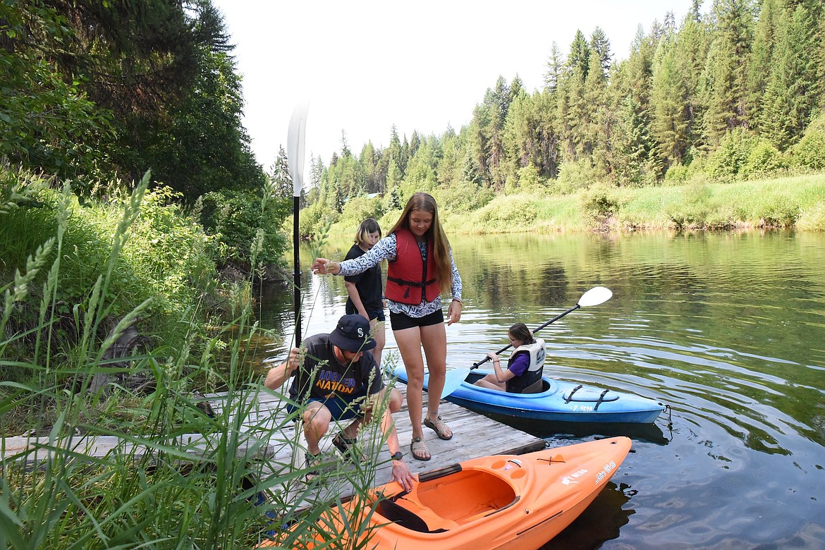 Ben Deremiah helping Rylee Delmas get into a kayak on the Yaak River. (Scott Shindledecker/The Western News)