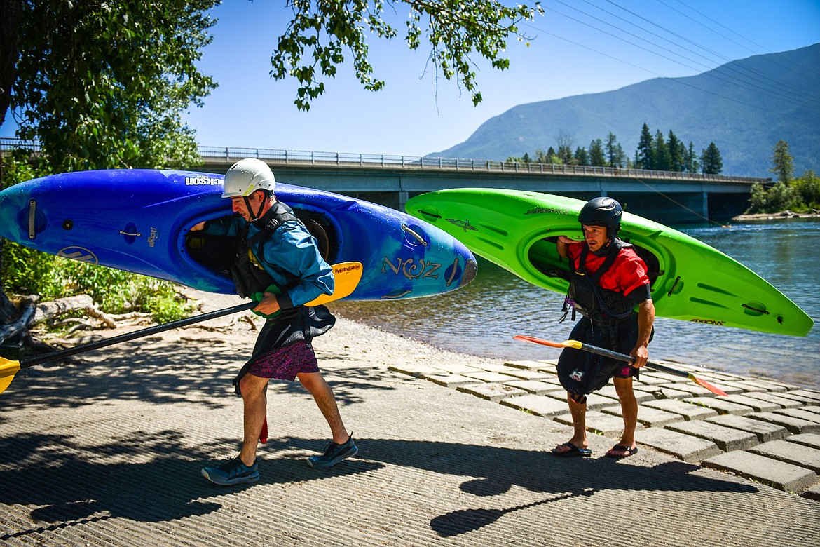 Dave Meyers, right, with Montana Kayak Academy, and Daily Inter Lake reporter Adrian Knowler carry their kayaks out of the Flathead River after a lesson at the Teakettle Fishing Access Site in Columbia Falls on Wednesday, July 19. (Casey Kreider/Daily Inter Lake)