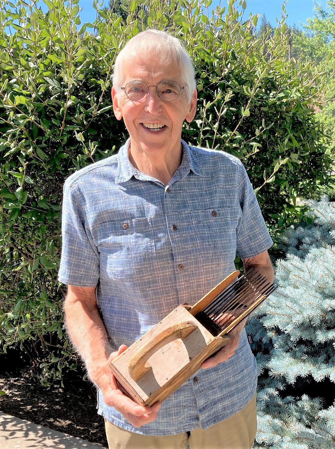 George Sayler holds Art Manley’s huckleberry picker.