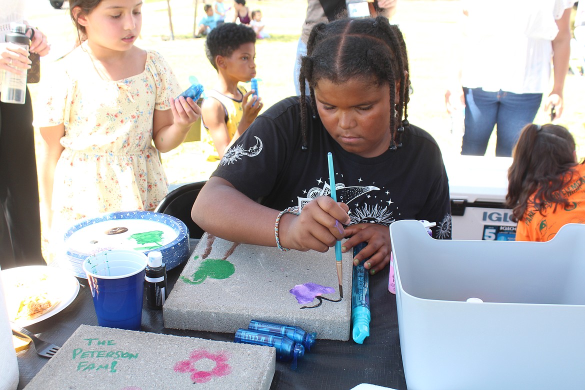 K’Shawni Holman adds detail to her paver painting at the dedication of the new Maple Grove Park. Attendees were invited to paint the pavers, which will be installed around the park’s picnic tables.