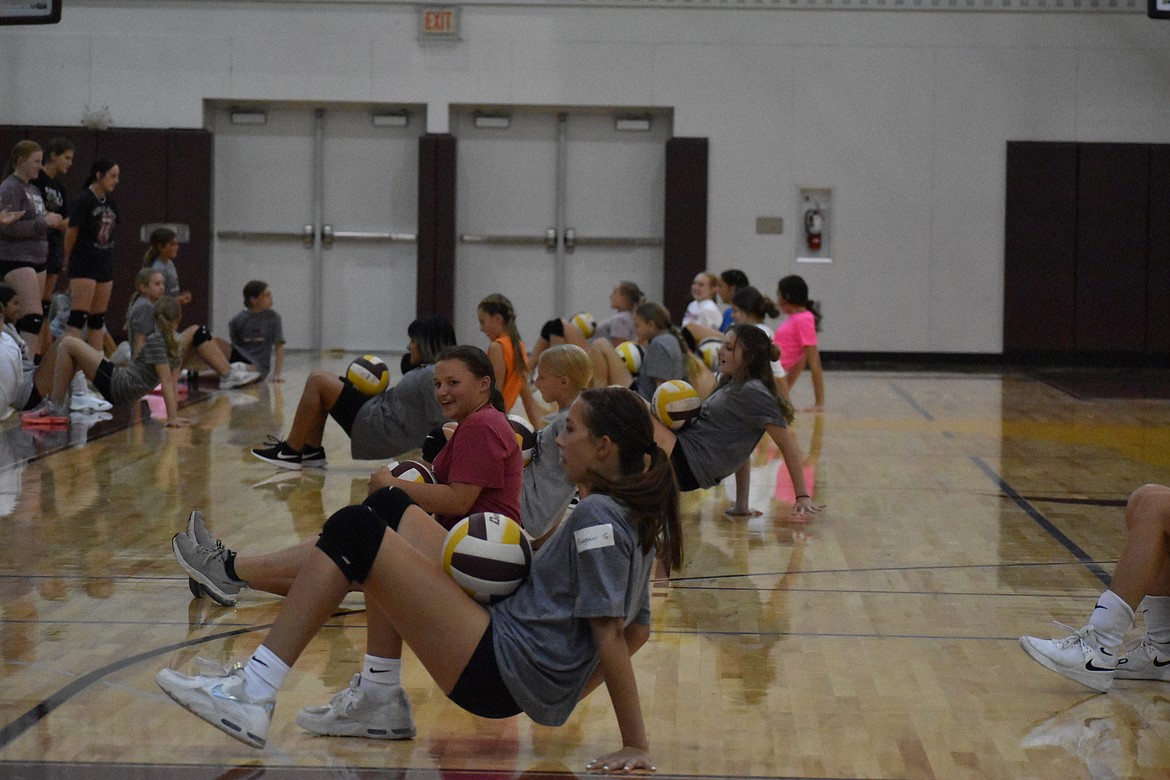 Campers at the Lil Mav volleyball camp participate in a crab walk challenge, where players attempt to keep the ball on top of them while crab walking.