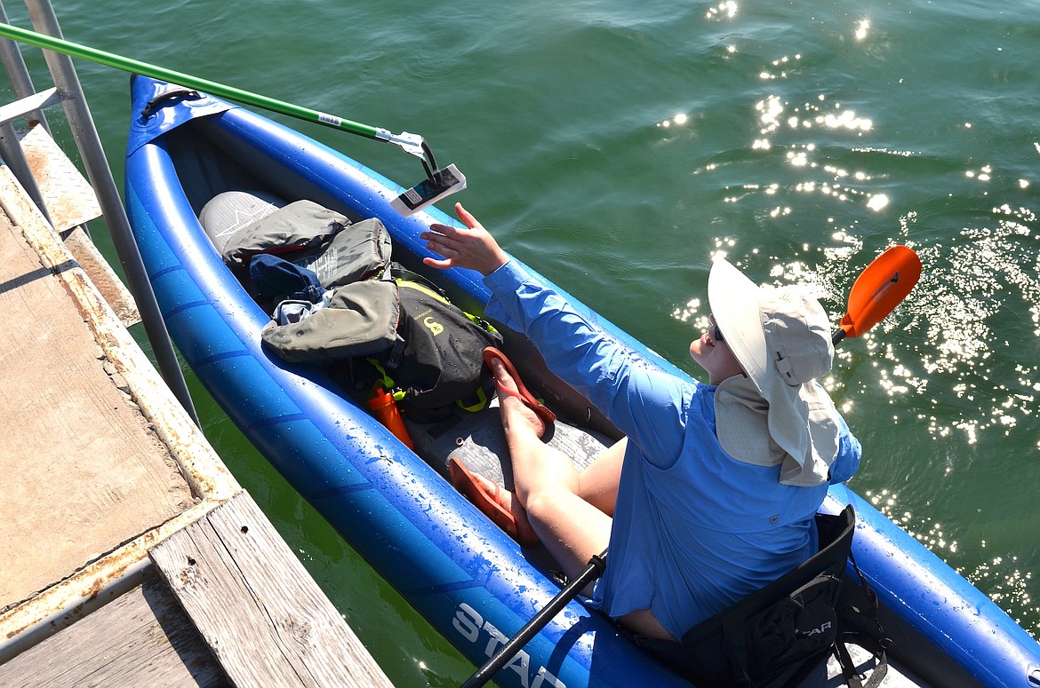 Poker Paddle participant Annie Retson reaches for her first poker card at KwaTaqNuk Resort. (Kristi Niemeyer/Leader)