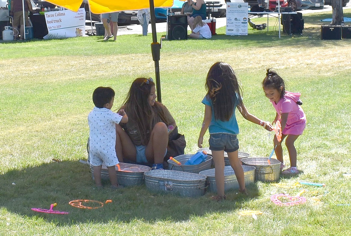 Twelve-year-old Allyson Marroquin keeps an eye on her siblings, from left, Mateo, 2, and Kailey and Camila, both 4, as they blow bubbles at the Downtown Moses Lake Association’s first Neppel Family Picnic Saturday.