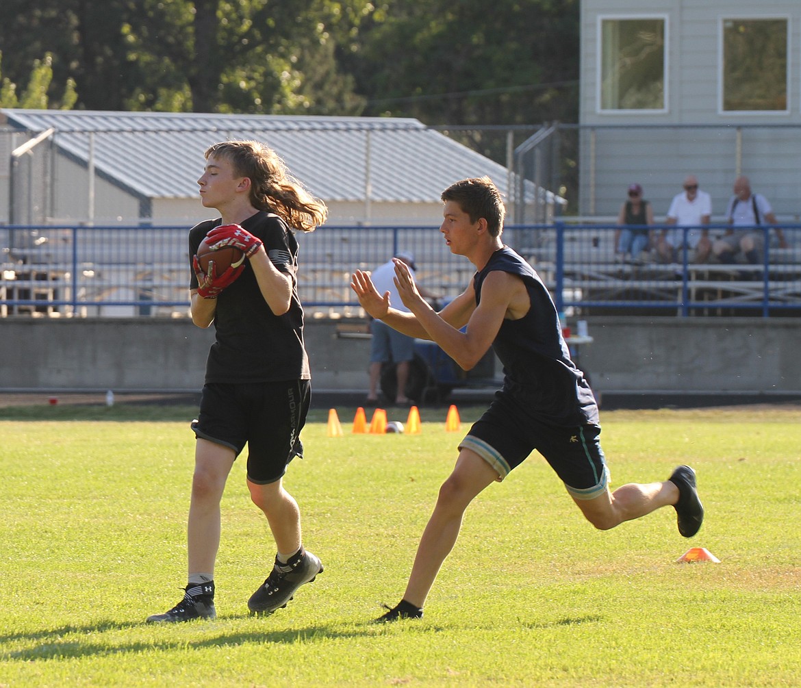 An athlete makes a catch in front of his defender after completing a route.