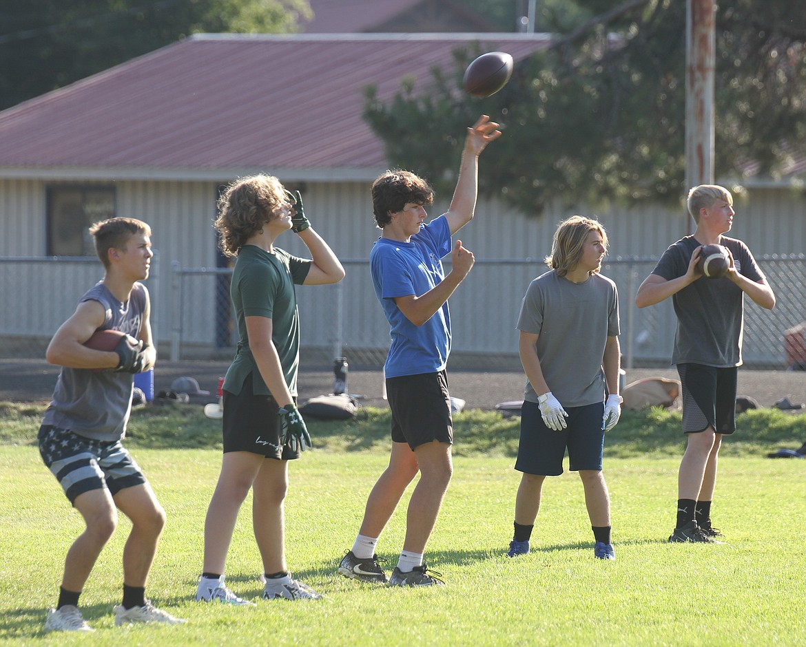 Aspiring quarterbacks throw footballs back and forth to one another after a water break on Friday.