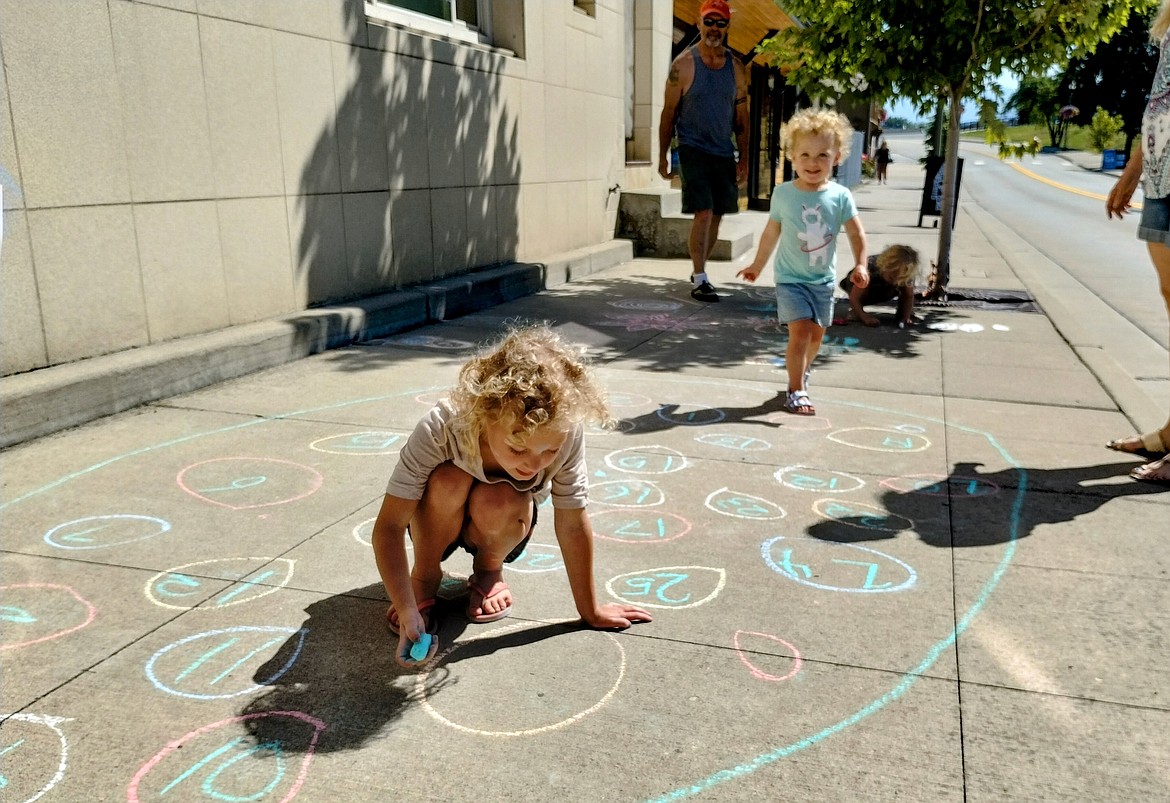 A young artist enjoys the Chalk the Block event for Kootenai River Days by decorating the sidewalk.