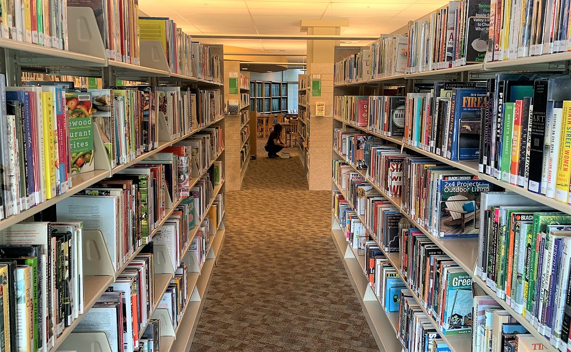 A person looks over books at the Coeur d'Alene Public Library on Tuesday. The library is looking to establish partnerships with local libraries to increase services.