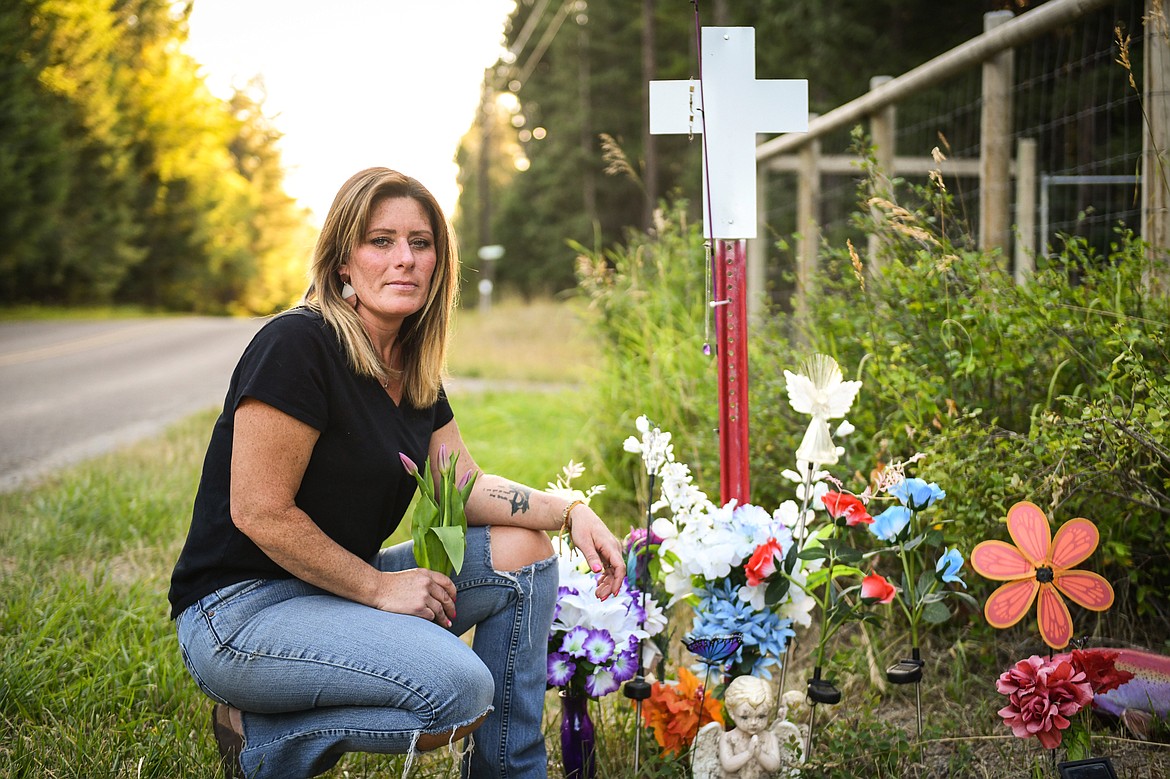 Jessie Hanson kneels next to the roadside cross memorial where her daughter Brooke was struck and killed by a drunk driver in Columbia Falls in May 2021. (Casey Kreider/Daily Inter Lake)