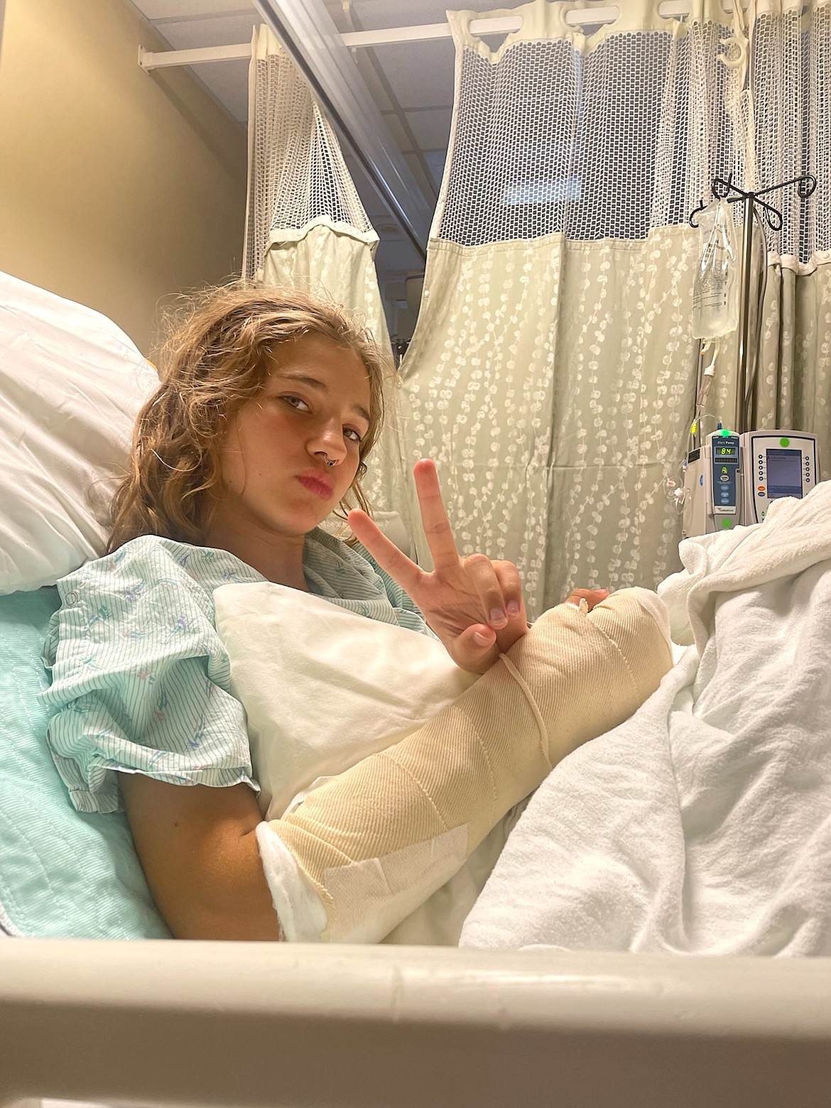 Bella Goodwin, 12, of Coeur d'Alene, flashes a peace sign from her hospital room last weekend after emergency surgery to reattach a finger that was severed from her right hand July 21 while playing on docks near Tubbs Hill. She is now home and recovering, with a cast up to her elbow.