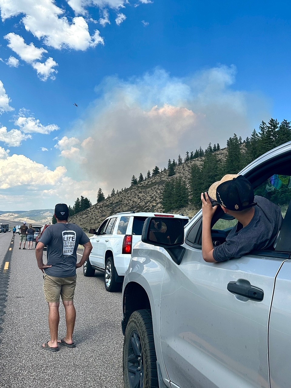 Vehicles stop along Montana 28 west of Elmo as air resources fly over the Niarada Fire on Sunday, July 30, 2023. (Mackenzie Gress photo)