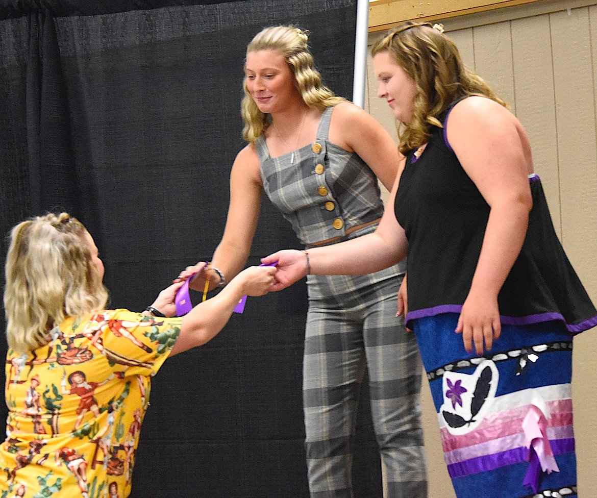 Taylor Mullen hands out Grand Champion and Reserve Champion ribbons to senior fashion revue competitors Brogan Youngren, left, and Ryanne Rider.
(Berl Tiskus/Leader)