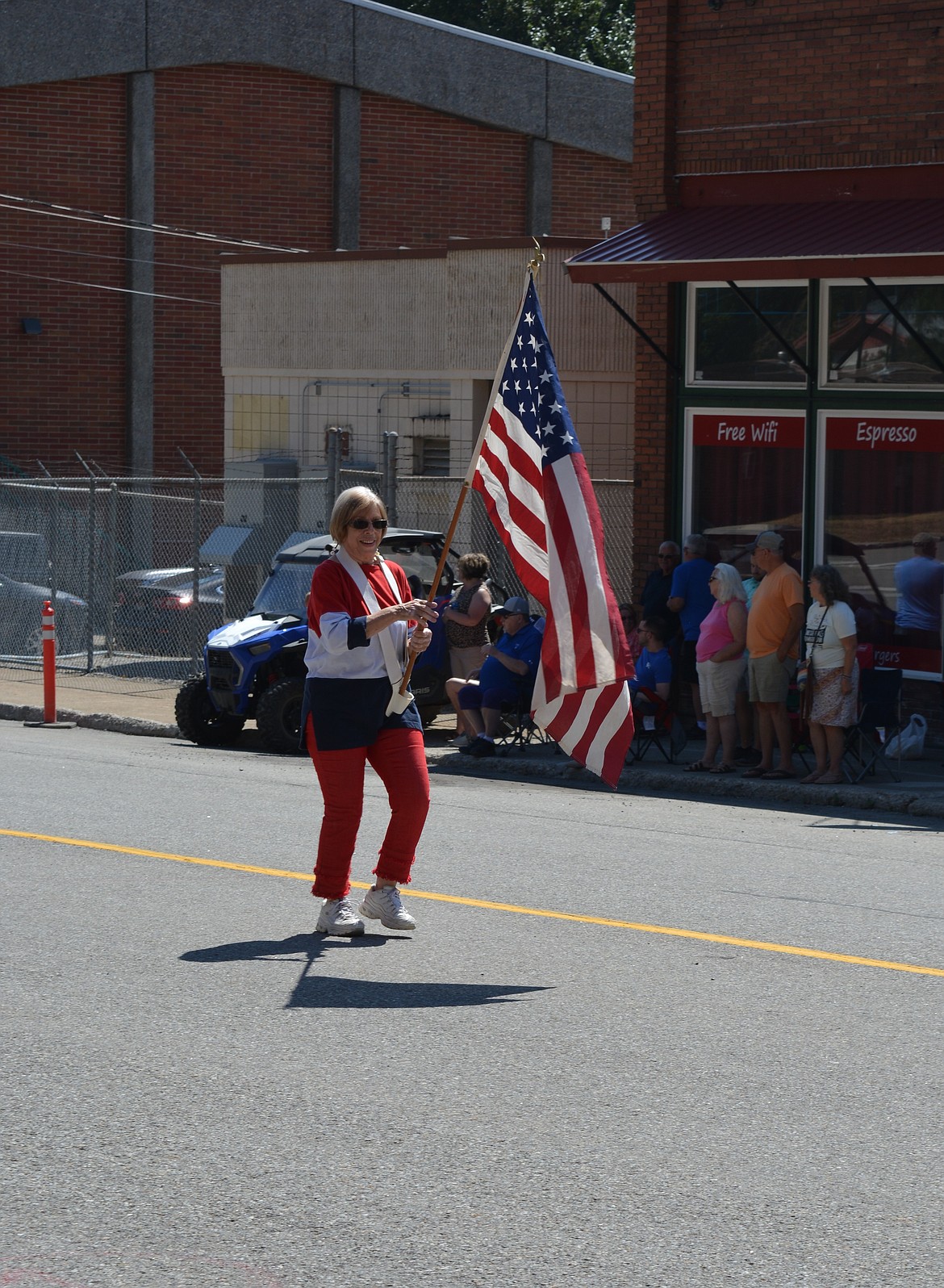 A woman bearing the American flag marches during the parade Saturday at Mullan Fireman's Fun Festival. The two-day celebration hosts competitions for adults and kids as part of a fundraiser for the Mullan Volunteer Fire Department.