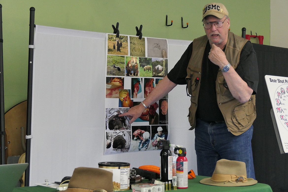 Hudson in front of a picture display board that shows photos of some of the bites from his mauling by a large brown bear.  He is pointing to the picture of a friend who was later killed by a bear in Alaska.  (Chuck Bandel/VP-MI)