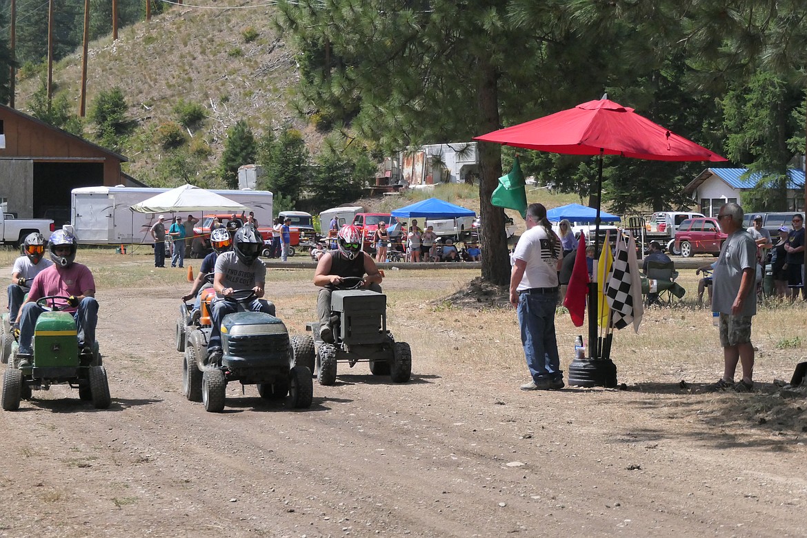 Race organizer Bradley McGuigan waves the green flag, sending several races off on the dusty track across from the Wild Coyote Bar and Grill during this year's riding lawn mower competition Saturday.  (Chuck Bandel/VP-MI)