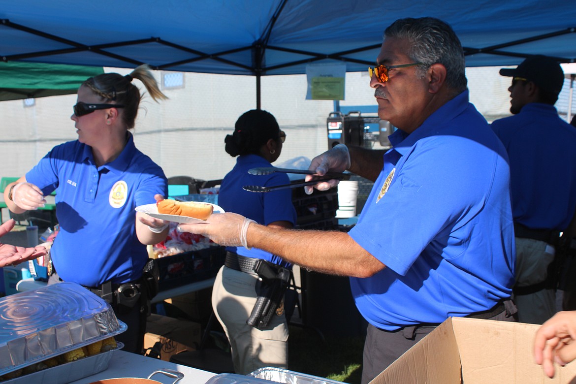 Quincy Police Detective Jazz Silva, left, and Officer Sal Mancini dish up hot dogs during National Night Out Monday.