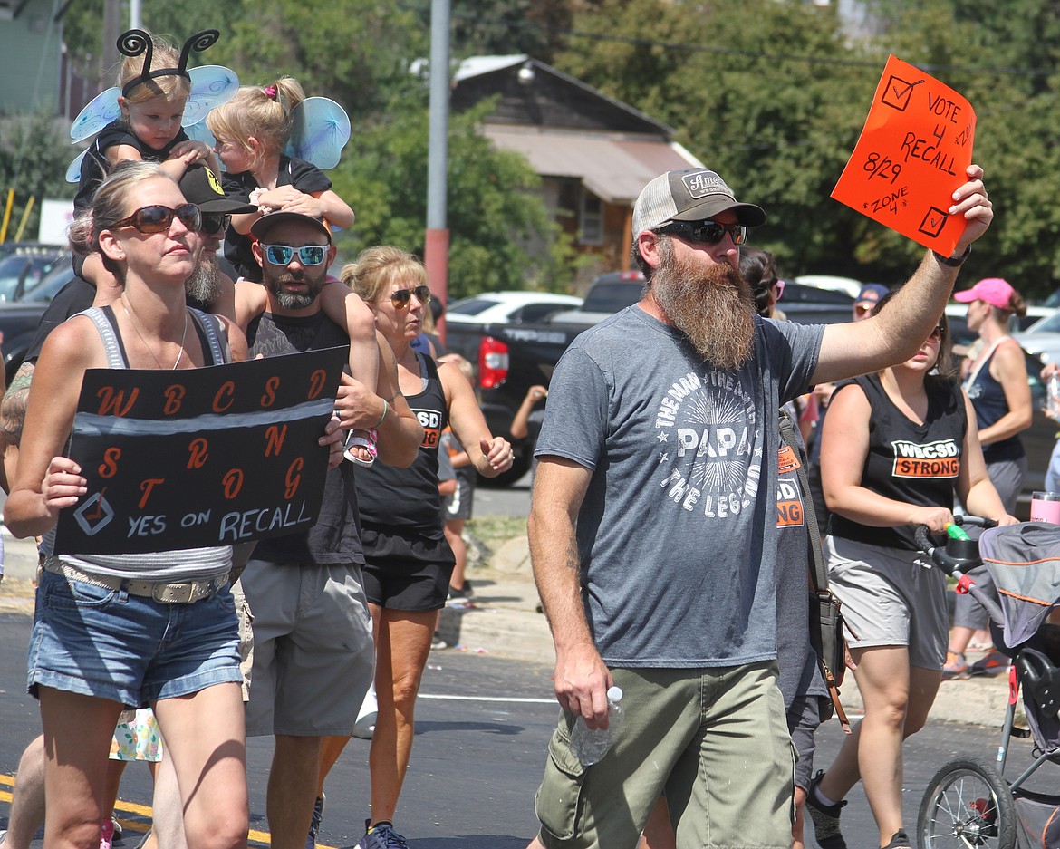 Two locals hold up recall signs near the end of the Timber Days parade on Saturday.