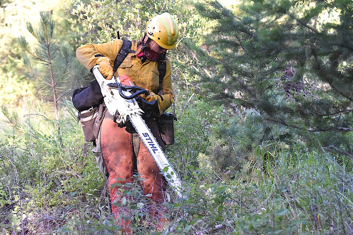 Rocky Mountain Fire Company's Bailey Gable runs a chain saw Wednesday morning while creating a line around the Gravel Pit Fire off U.S. 2 near Silver Butte Road in Lincoln County. (Scott Shindledecker/The Western News)