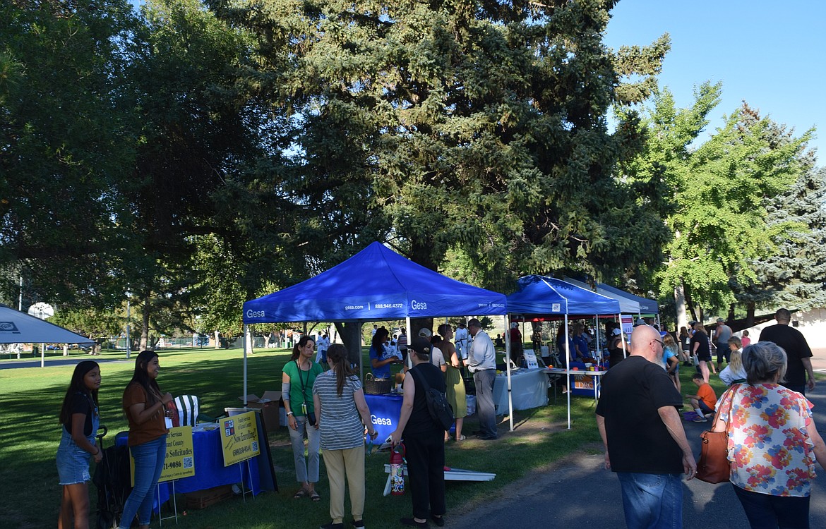 Members of the public browse informational booths on local organizations, including several devoted to resources related to public safety and crime prevention, the subjects of National Night Out.